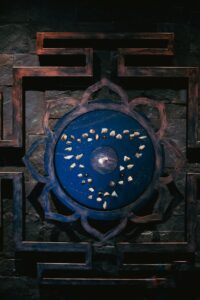 Intricate blue mandala with decorative stones on wooden background.